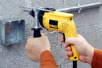 Taladro percutor DEWALT DW508S-B3 perforando muro de bloque con barra de profundidad