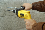 Taladro percutor DEWALT DW508S-B3 en uso sobre pared de concreto