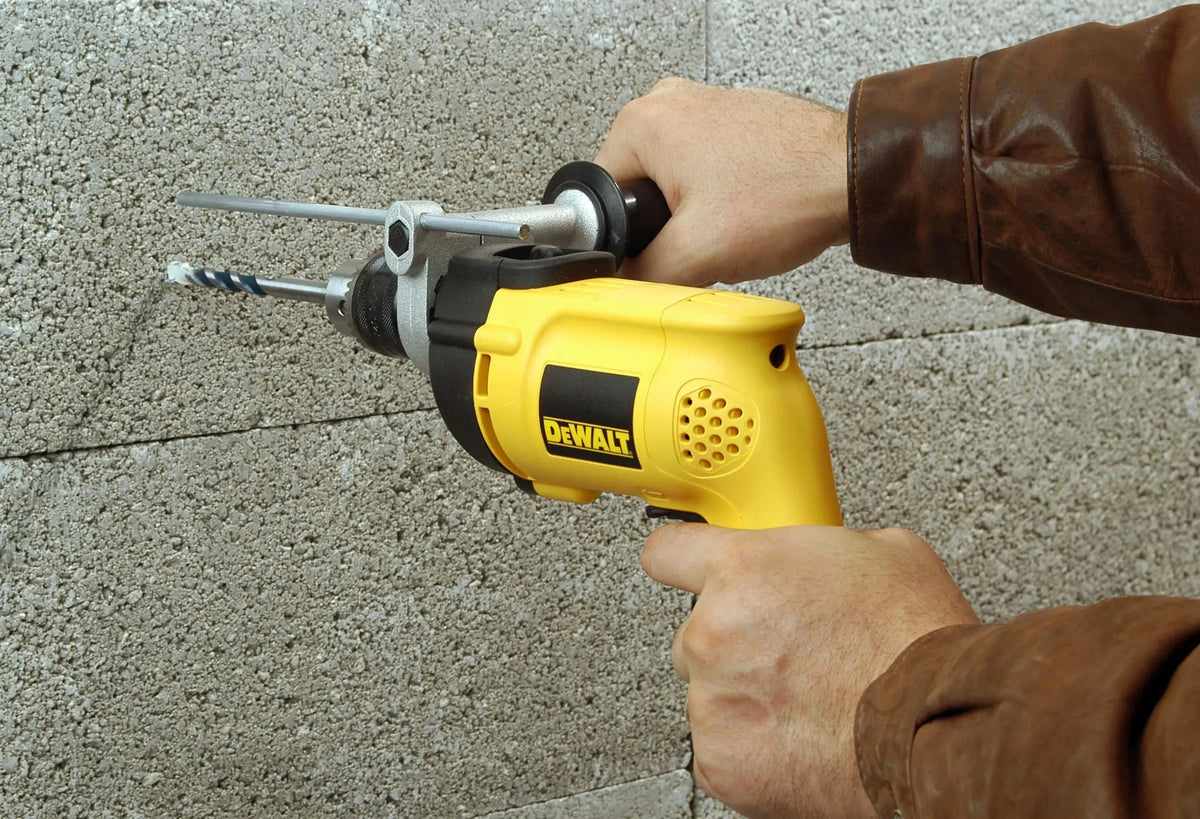 Taladro percutor DEWALT DW508S-B3 en uso sobre pared de concreto